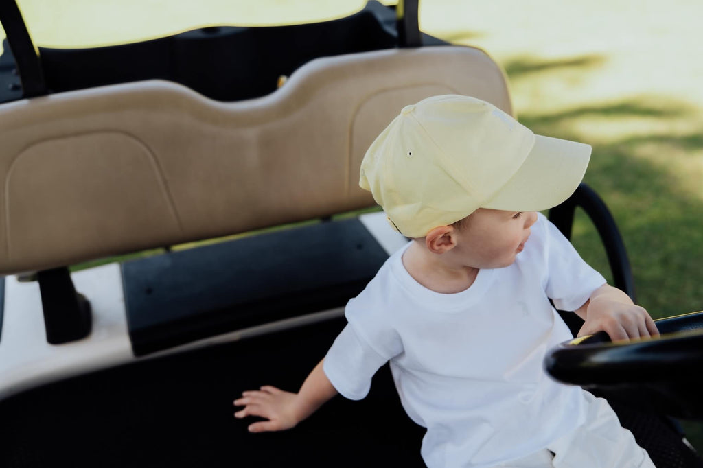 Child wearing white tee and yellow cap.