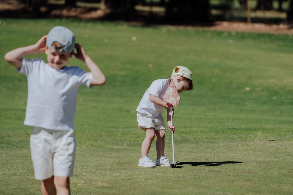 Two children playing golf on a grassy field