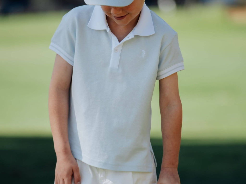 Child wearing a light blue polo shirt on the golf course.