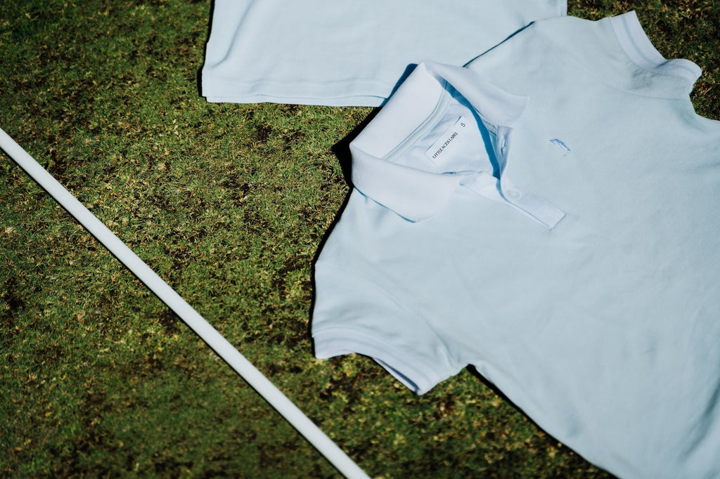 Light blue polo shirt on grass with a white golf club