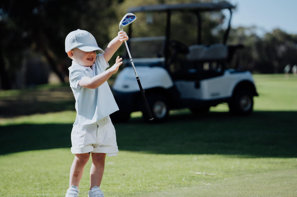 Child wearing a light blue polo shirt on the golf course.