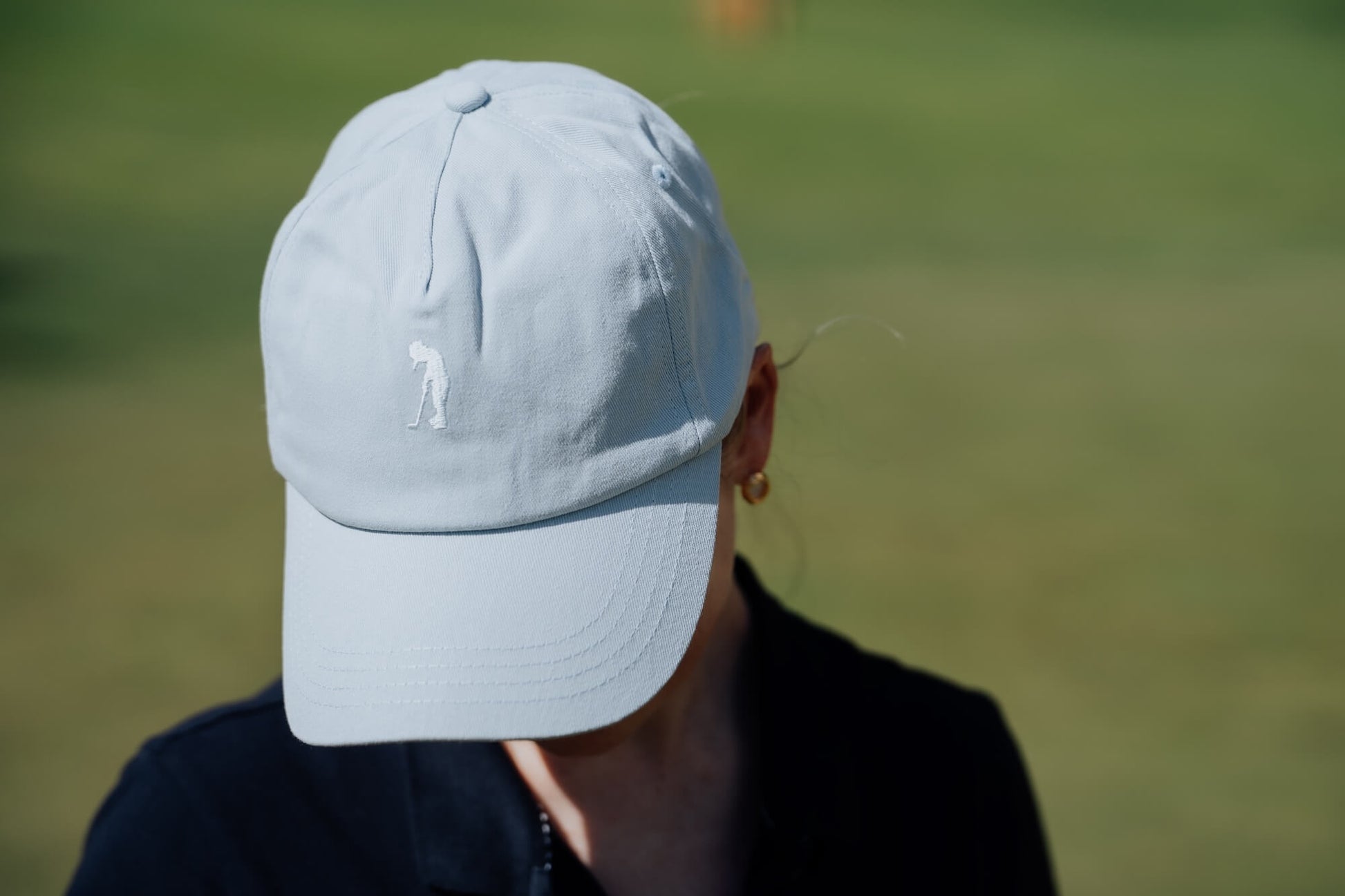 Person wearing a light blue cap with a blurred green background