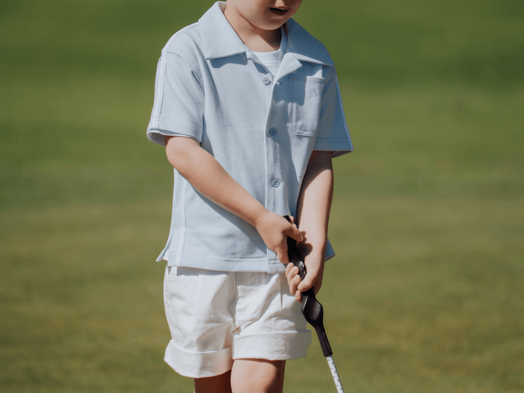 Child wearing blue button up shirt and playing golf.