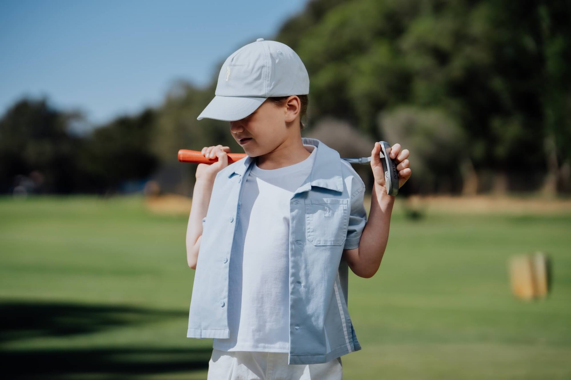 Child wearing blue button up and playing golf.