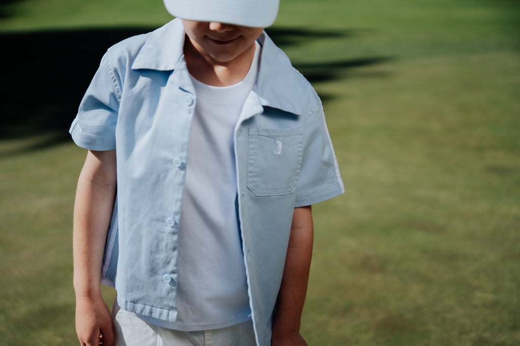 Child wearing blue button up and playing golf.