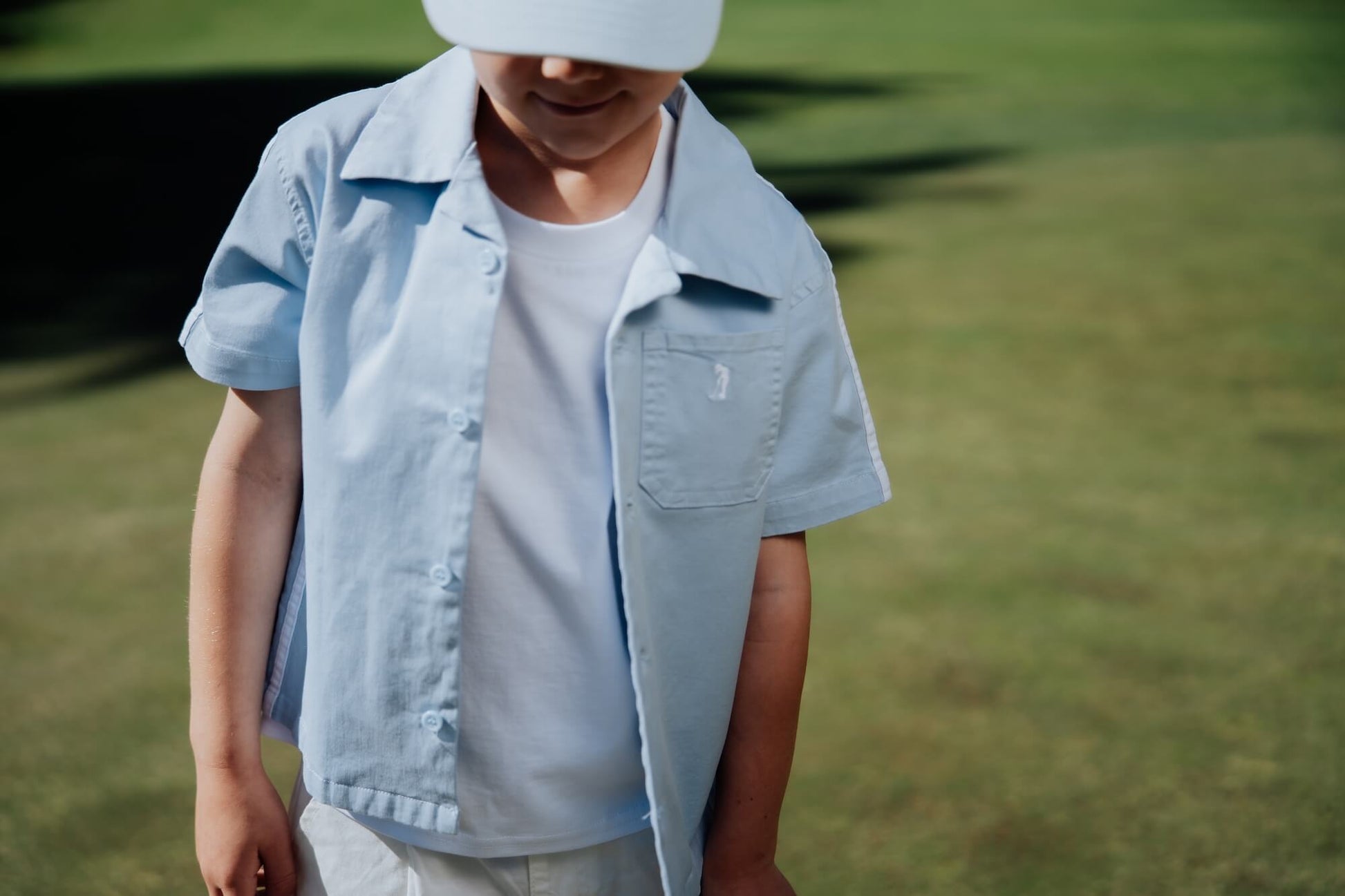 Child wearing blue button up and playing golf.