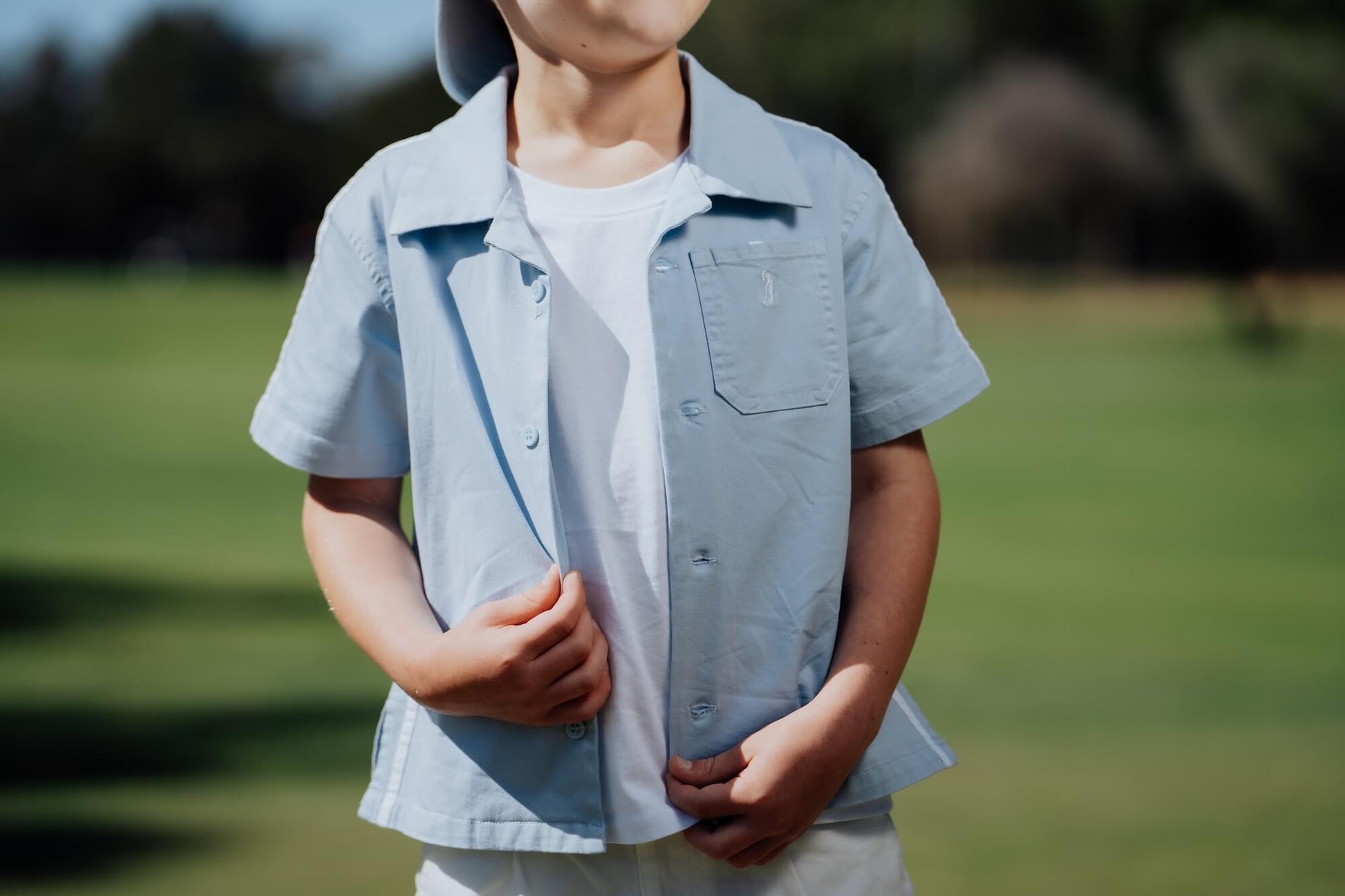 Child wearing blue button up and playing golf.