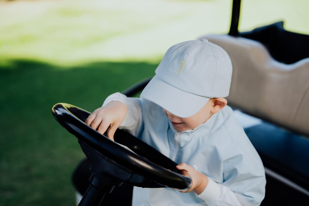 Child in block style blue and white windbreaker on golf cart.