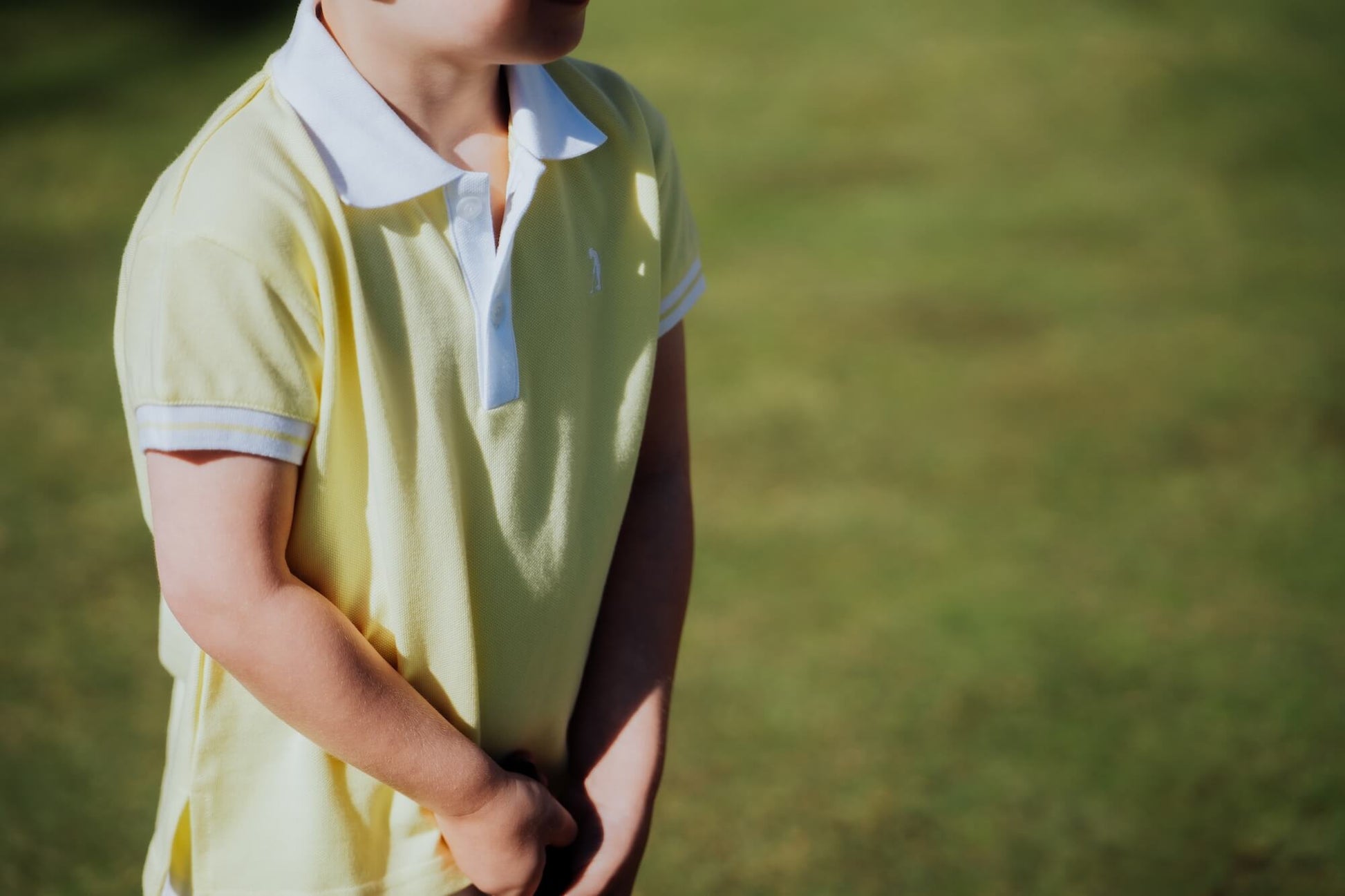 Child wearing yellow polo and playing golf.