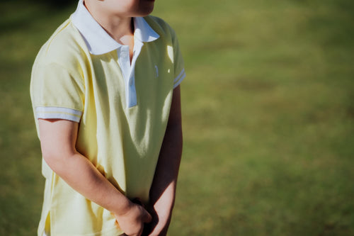 Child wearing yellow polo and playing golf.