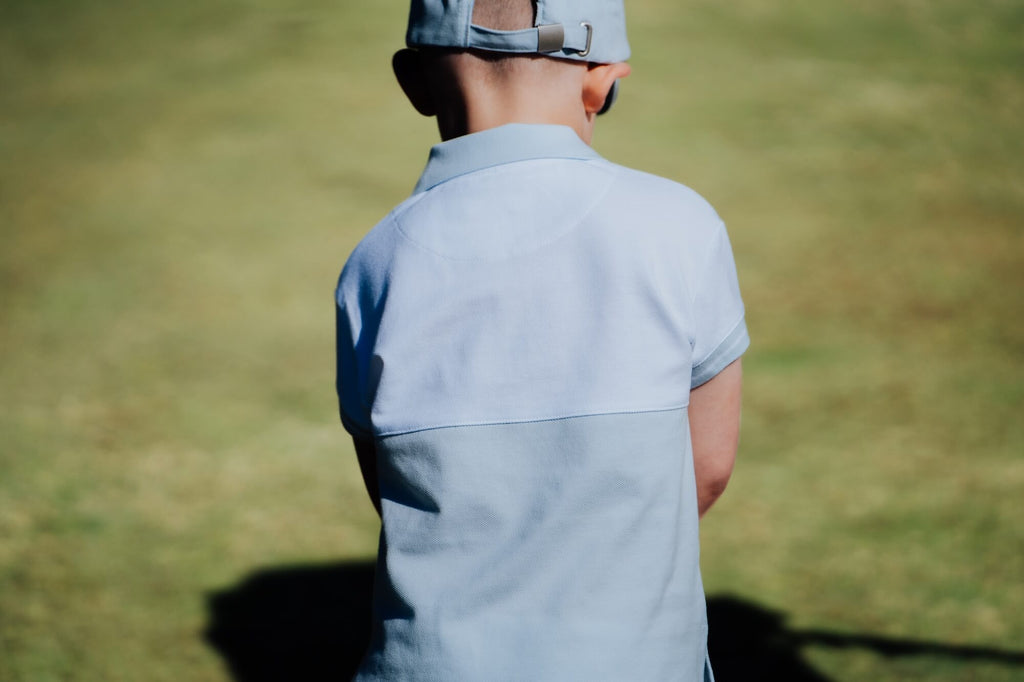 Child wearing blue and white polo and playing golf.