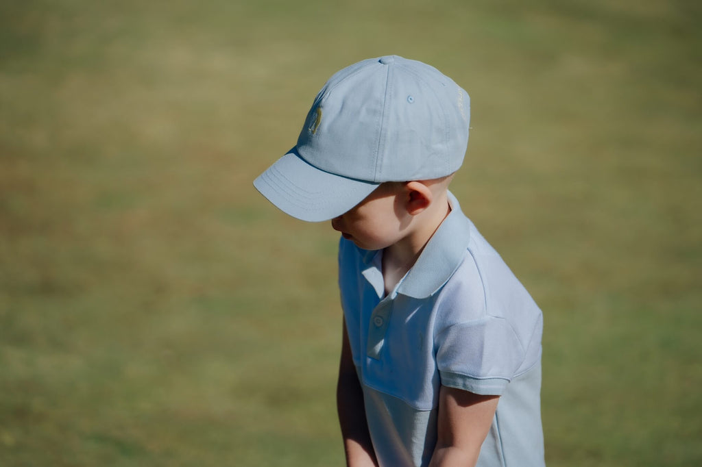 Child wearing blue and white polo and matching blue cap and playing golf.