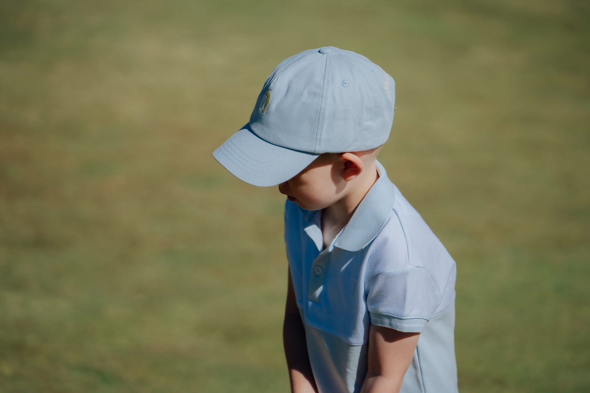 Child wearing blue and white polo and matching blue cap and playing golf.